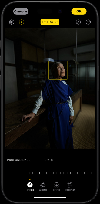 iPhone 15 Pro mostrando o retrato de uma mulher tirado em um ambiente com pouca luz e o ponto de foco ajustável em seu rosto.