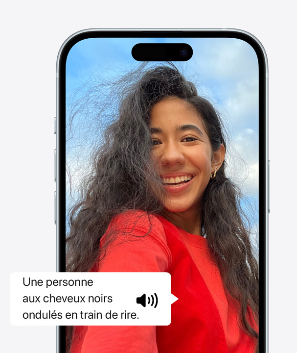 Image d’iPhone illustrant l’utilisation de VoiceOver pour décrire une personne aux cheveux ondulés en train de rire à l’écran.