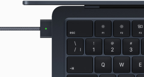 Vue du dessus d’un MacBook Air minuit auquel est branché un câble MagSafe de la même couleur
