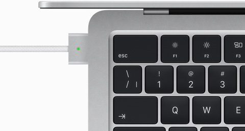 Vue du dessus d’un MacBook Air argent auquel est branché un câble MagSafe de la même couleur