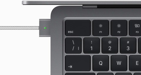 Vue du dessus d’un MacBook Air gris cosmique auquel est branché un câble MagSafe de la même couleur