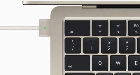 Vue du dessus d’un MacBook Air comète auquel est branché un câble MagSafe de la même couleur