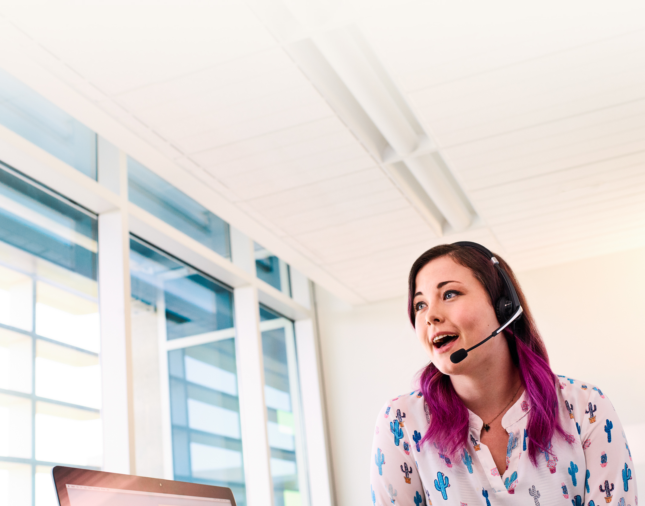 A female Apple Support Advisor stands as she speaks to a customer through a phone headset.