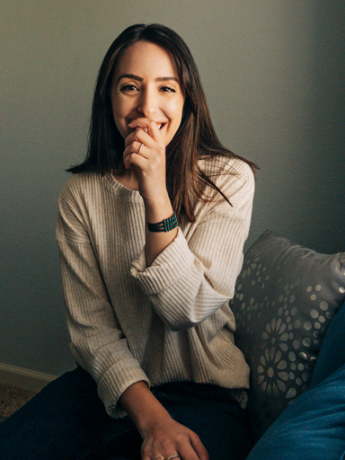 Fotoportret van Belqise, die de lezer met haar hand voor de mond lachend aankijkt.