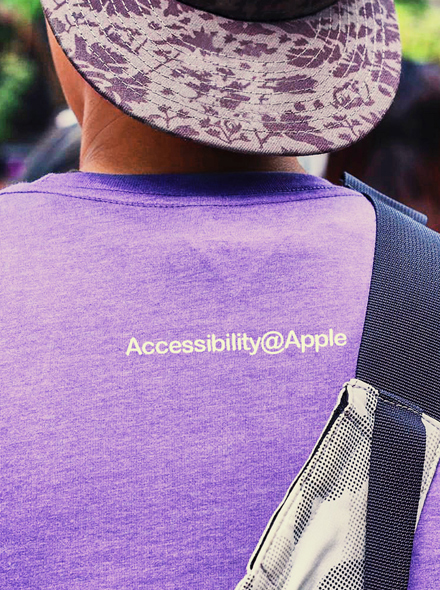一个人的背影照片，此人穿着的 T 恤印有 Accessibility@Apple 字样。