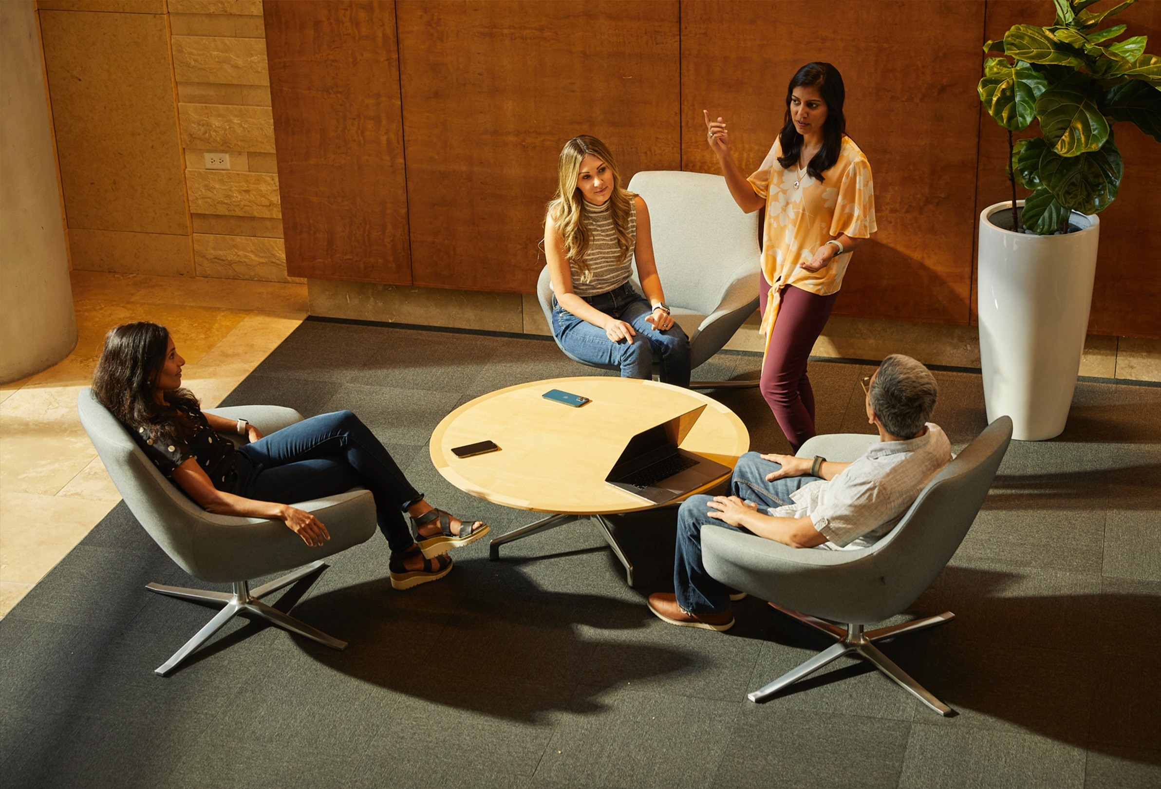 여유로운 공동 작업 공간에 함께 앉아 이야기를 나누고 있는 네 명의 Apple 직원들.
