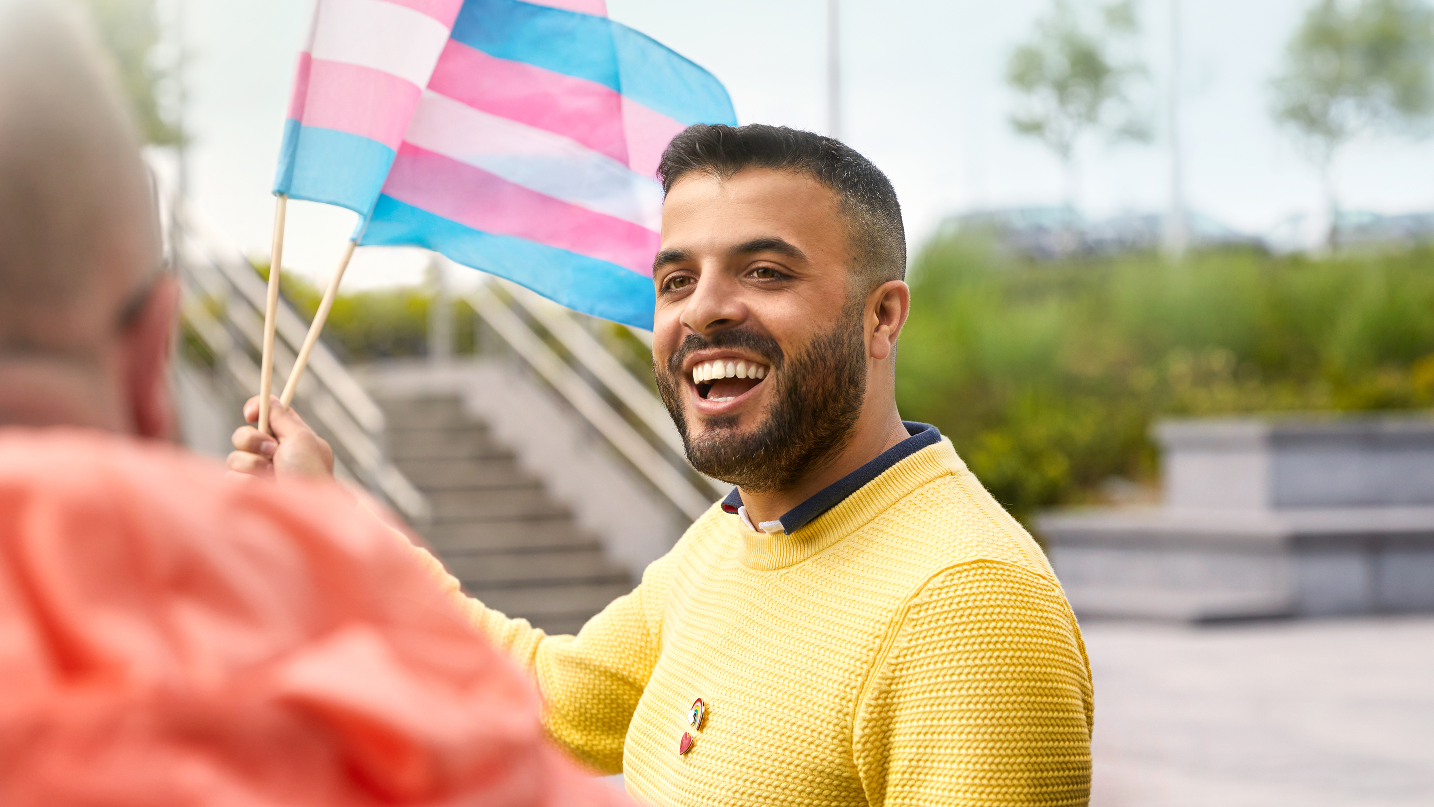 Uma pessoa que trabalha na Apple Cork com uma bandeira da comunidade transgênero.