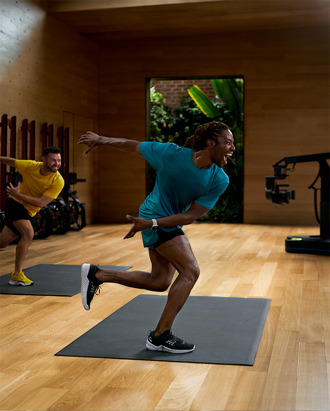 Apple Fitness+ trainers leading a session in front of cameras in a video studio. 
