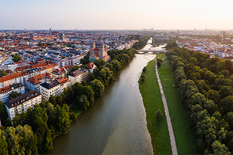 Vista aérea de Munique com um rio, árvores e uma trilha margeando o rio.