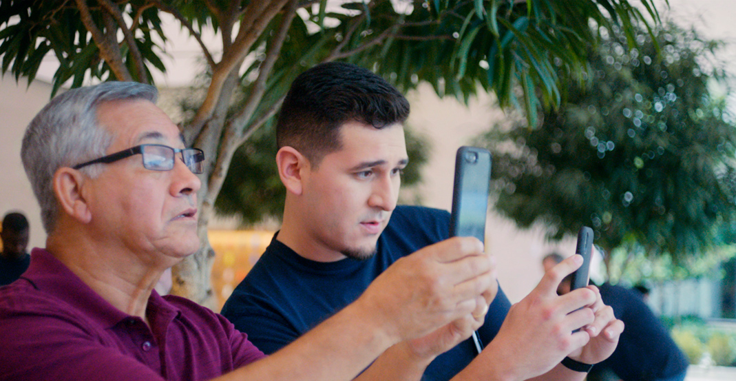 테크니컬 스페셜리스트인 제로니모가 Apple Store 고객에게 iPhone 카메라 사용 방법을 보여주고 있습니다.