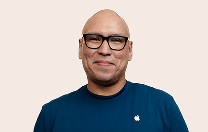 Funcionário da Apple Retail com óculos pretos sorrindo para a câmera.