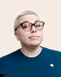 Apple Retail-medewerker met kort haar en een bril die in de camera kijkt.
