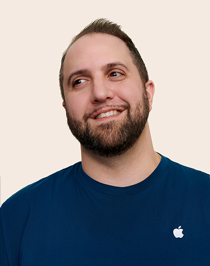 Apple Retail-medewerker die glimlachend wegkijkt van de camera.