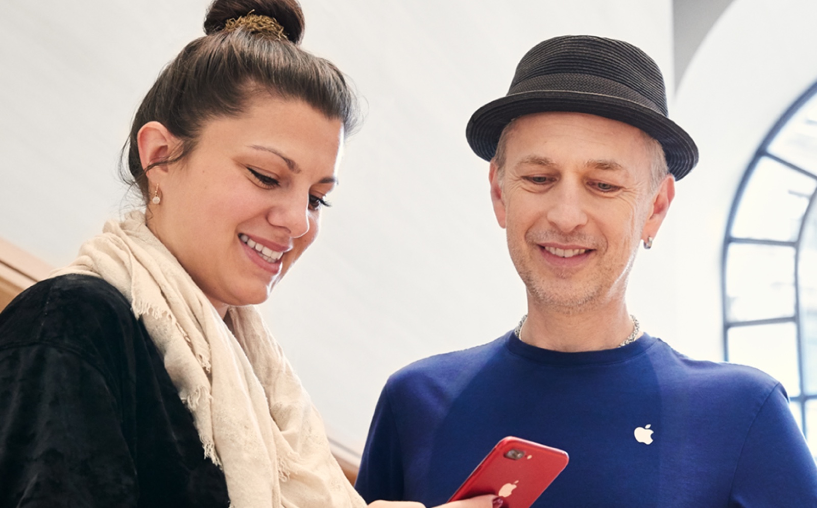 Apple Store에서 남성 직원이 iPhone 기능에 대해 고객을 지원하는 모습