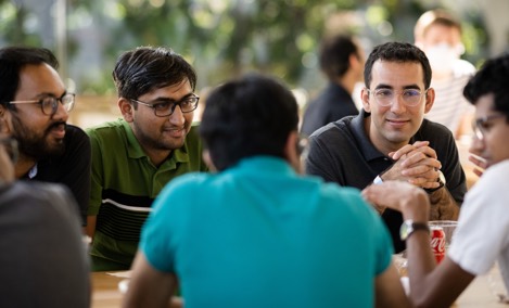  นักศึกษาฝึกงานของ Apple กลุ่มหนึ่งกำลังสนทนากันที่โต๊ะใน Caffè Macs