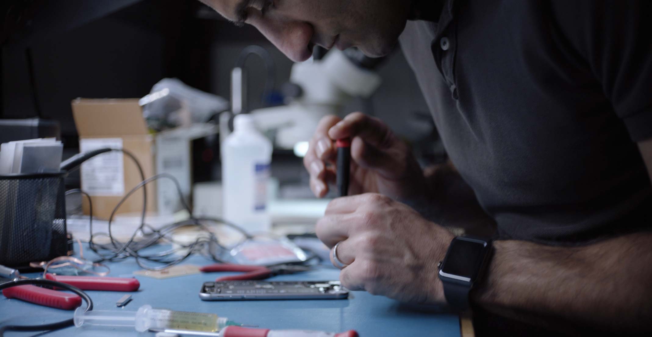 O Ehsan, gerente de engenharia do grupo de Sensing Product Design da Apple, trabalha em um iPhone em um laboratório de engenharia.