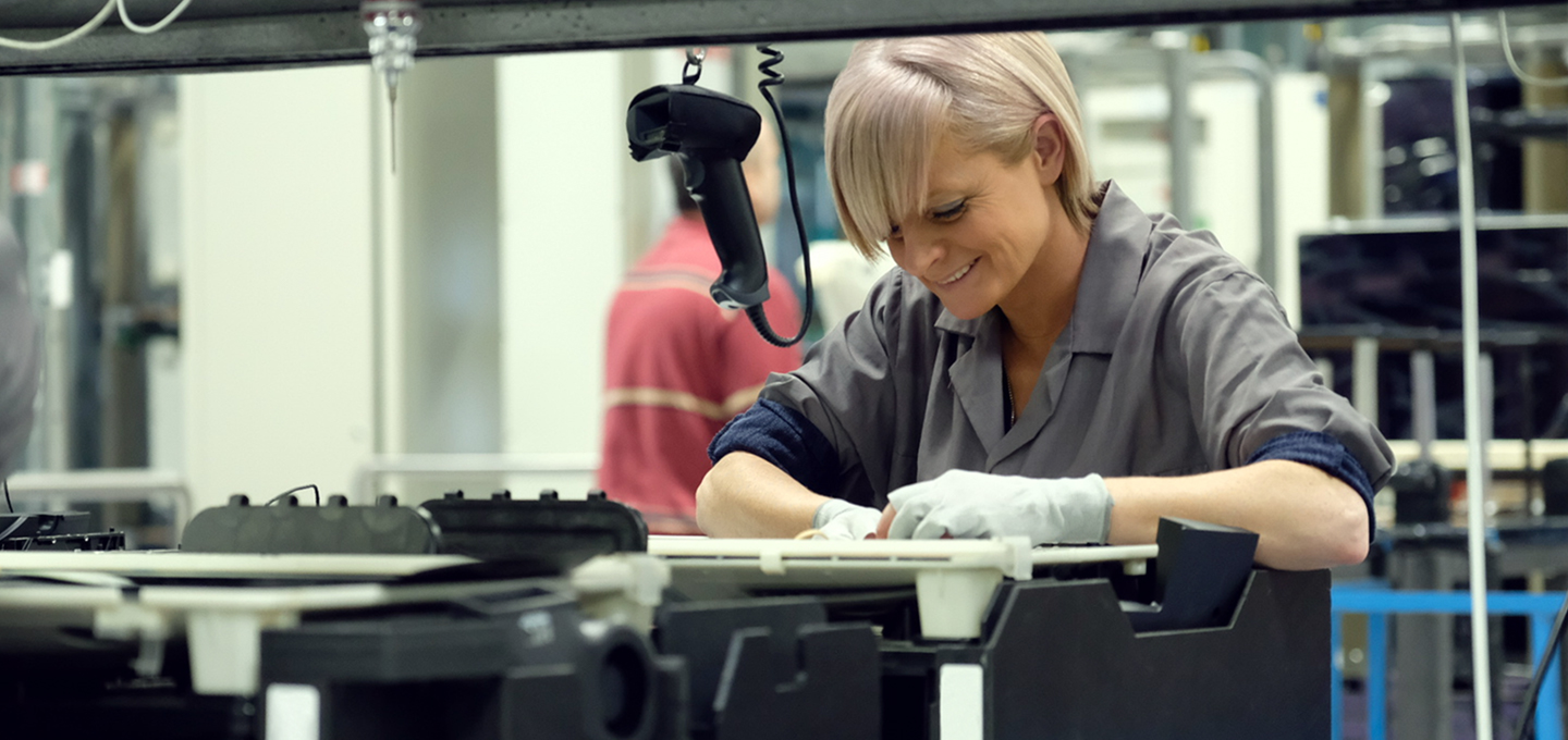 在 Apple 的生产设施内，两位员工正在检查阳极氧化钛合金架上的 MacBook 铝合金外壳