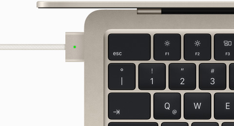Imagen desde arriba de un cable MagSafe conectado a un MacBook Air blanco estelar