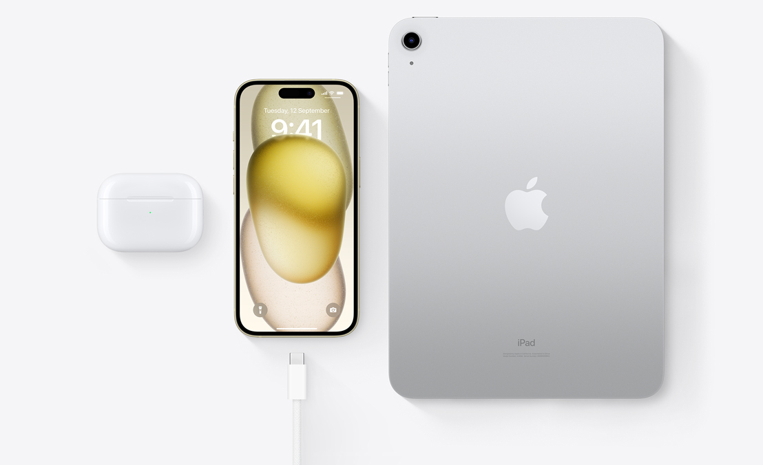 A bird’s-eye view of AirPods Pro, iPhone 15 and an iPad with a USB-C connector to demonstrate how all three devices can be charged using the same USB-C cable.