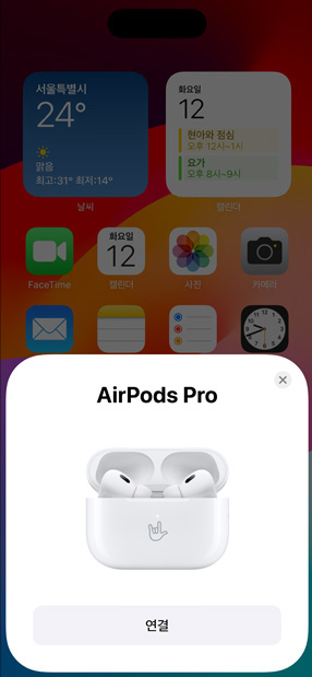 AirPods Pro가 들어 있는 MagSafe 충전 케이스를 iPhone 옆에 둔 모습. iPhone 홈 화면의 작은 타일에 눌러서 AirPods을 쉽게 페어링할 수 있는 ‘연결’ 버튼이 팝업으로 표시된 모습.