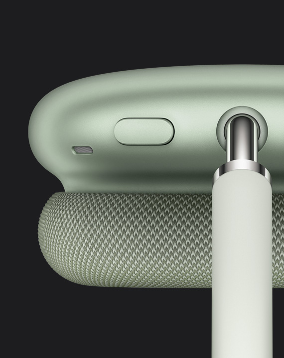 綠色 AirPods Max 耳罩頂部的細節，展示噪音控制按鈕設於頂篷接合點旁邊。