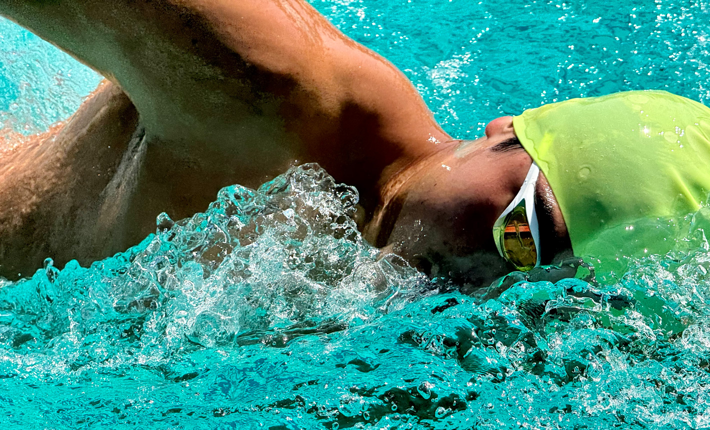 Et meget detaljeret billede af en svømmer i en pool, hvor der er zoomet ind, og vandet sprøjter omkring ham