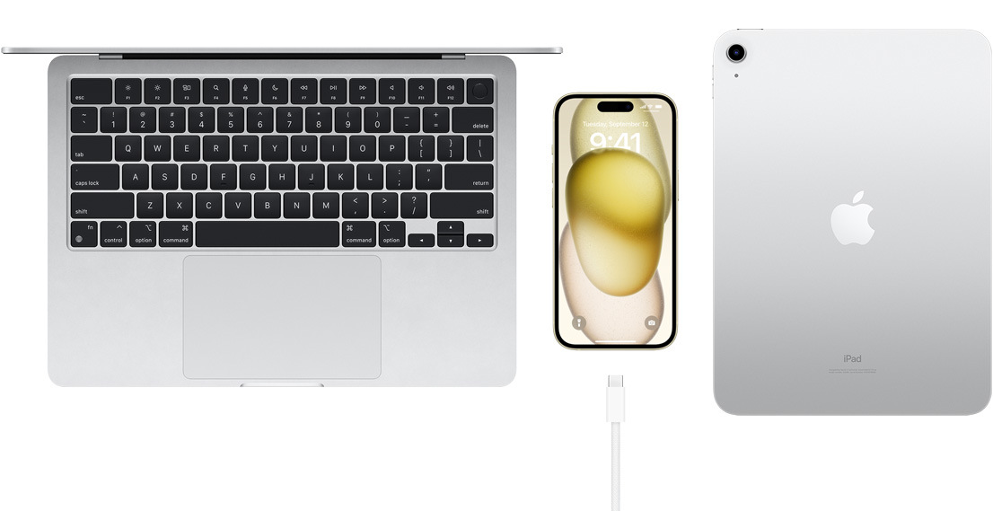 Tampilan atas MacBook Pro, iPhone 15 dengan konektor USB-C, dan iPad
