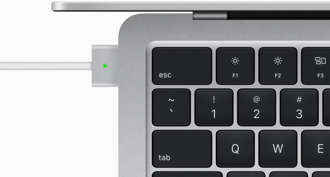 Felülnézeti közelkép a MacBook Air ezüstszínű modelljéről a hozzá csatlakoztatott MagSafe kábellel