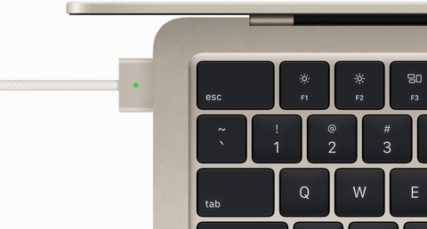 Felülnézeti közelkép a MacBook Air csillagfényszínű modelljéről a hozzá csatlakoztatott MagSafe kábellel