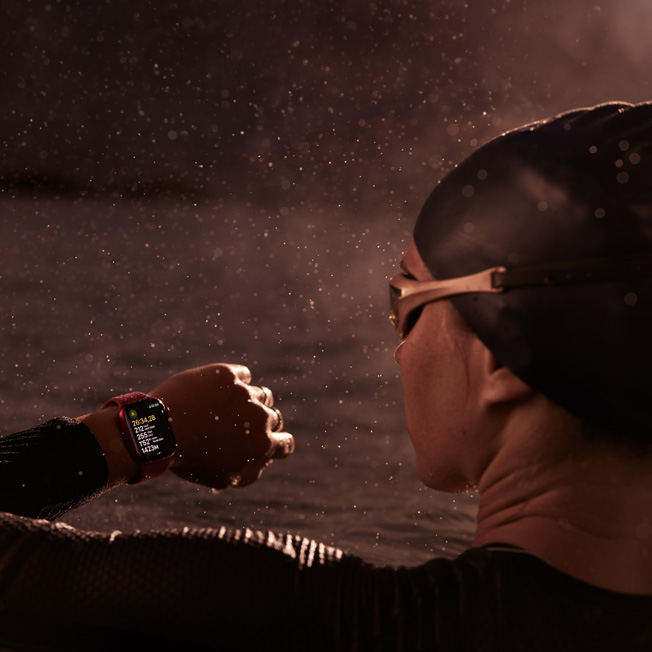Hình ảnh của một vận động viên bơi lội trong bể bơi, đang nhìn vào Apple Watch của mình.
