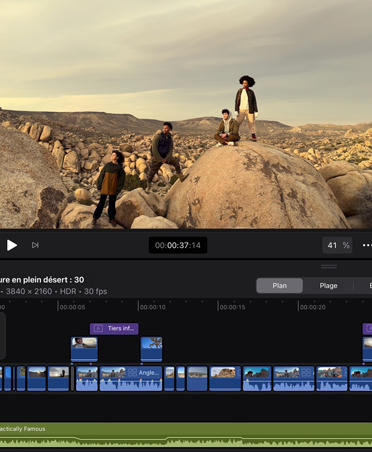 Un iPad Pro, face avant, orientation portrait, noir infini, écran affichant une app de retouche vidéo avec une image de personnes posant sur des rochers dans un paysage désertique, timeline, outils de retouche