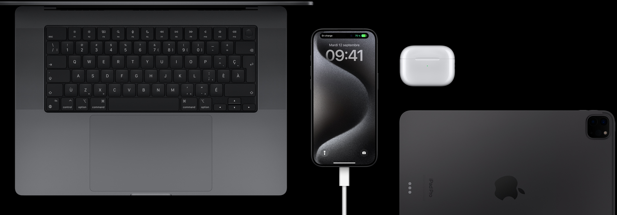 iPhone 15 Pro branché à un câble USB-C et entouré d’un MacBook Pro, d’AirPods Pro et d’un iPad