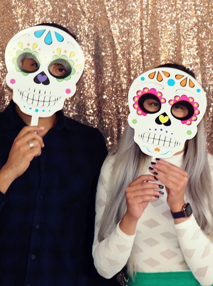 Photo portrait of two people wearing Día de Muertos masks.