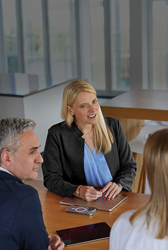 Drei Mitglieder des Apple Sales und Business Development Teams unterhalten sich an einem Tisch in einem Gemeinschaftsbereich.