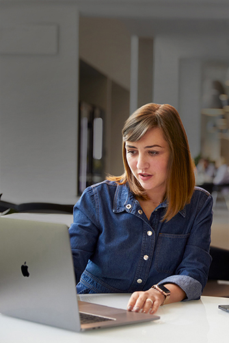 Ein Mitglied des Apple Support und Service Teams arbeitet in einem Gemeinschaftsbereich an einem MacBook.