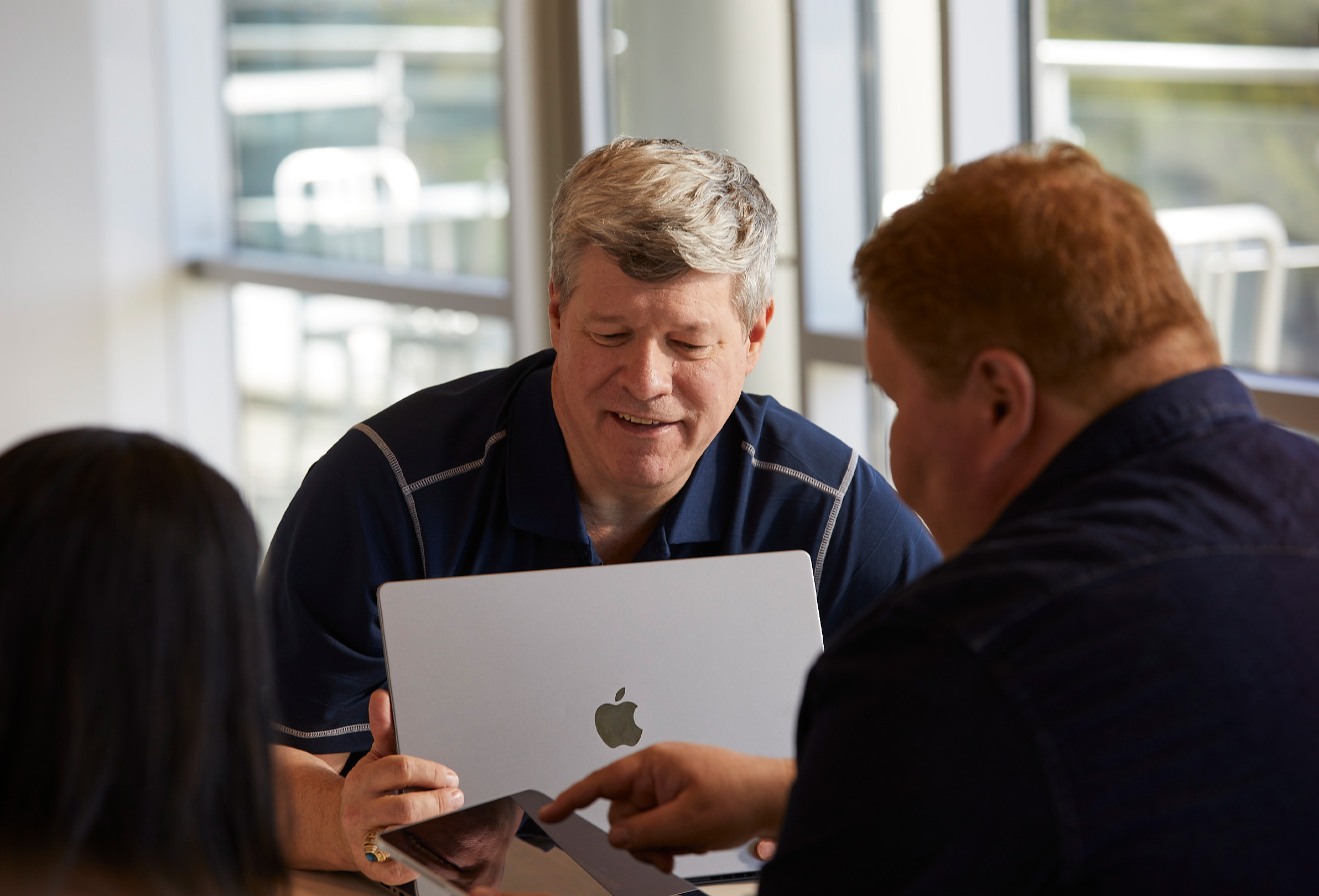 MacBook과 iPad를 사용하며 함께 일하고 있는 세 명의 Apple 직원.