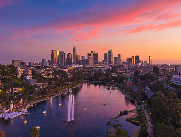 Aerial view looking towards Los Angeles skyscrapers with a park and a lake in the foreground.