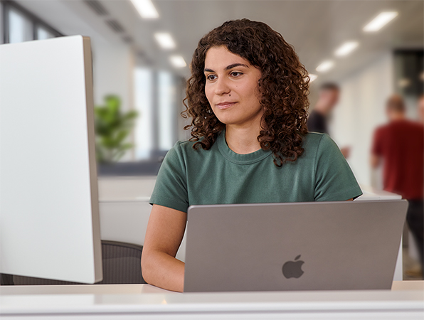 An Apple team member using a MacBook and Studio Display in an office.