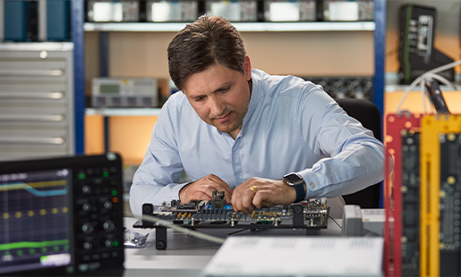 Greg 在硬件工程實驗室內工作，周圍滿是晶片測試設備。