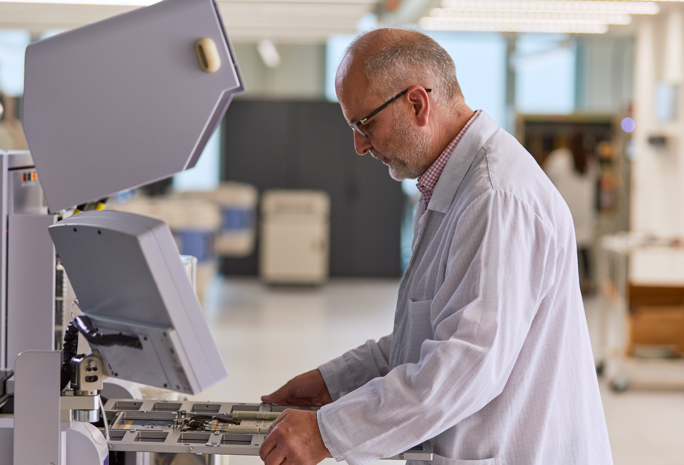 Un employé Apple vêtu d’une blouse blanche de laboratoire manipule des équipements techniques. 