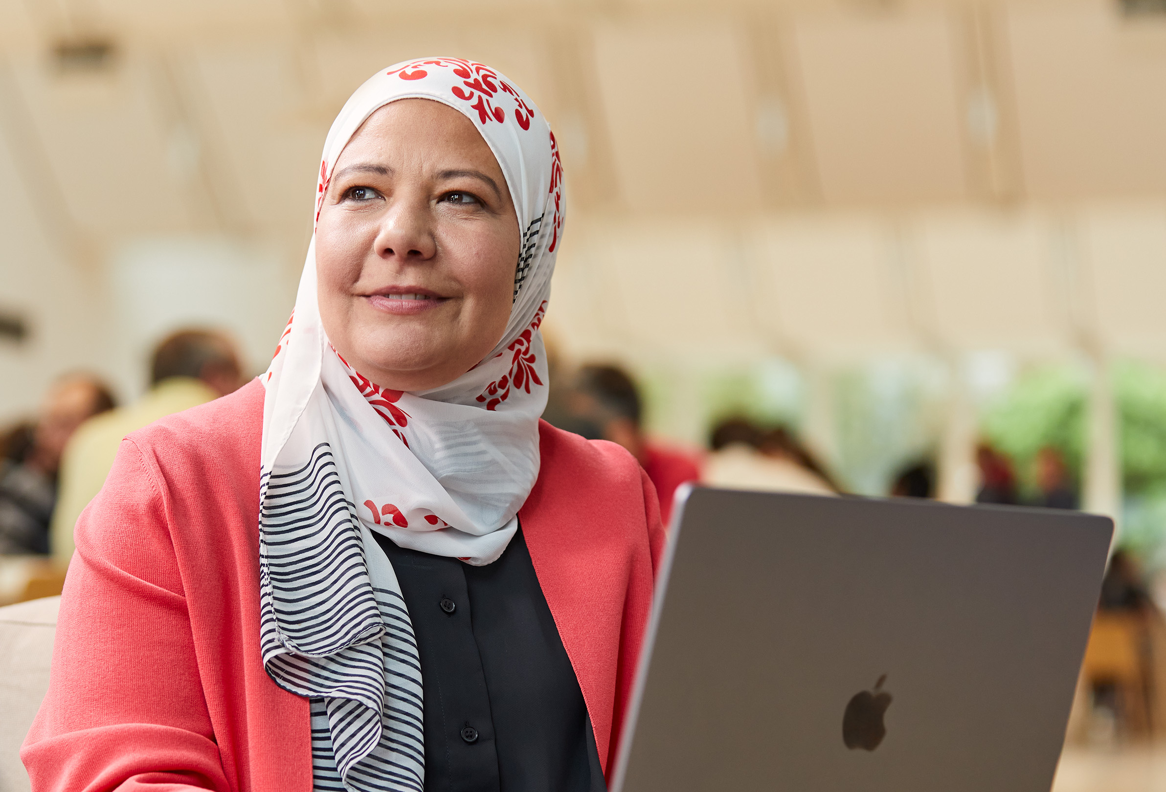 Una empleada de Apple sentada y viendo a la izquierda mientras trabaja en su MacBook.