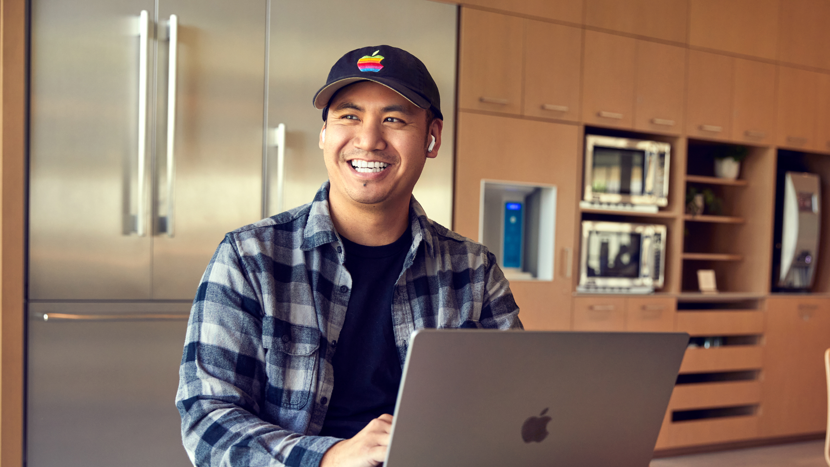En Apple San Diego-medarbetare som ler och jobbar på sin bärbara dator.