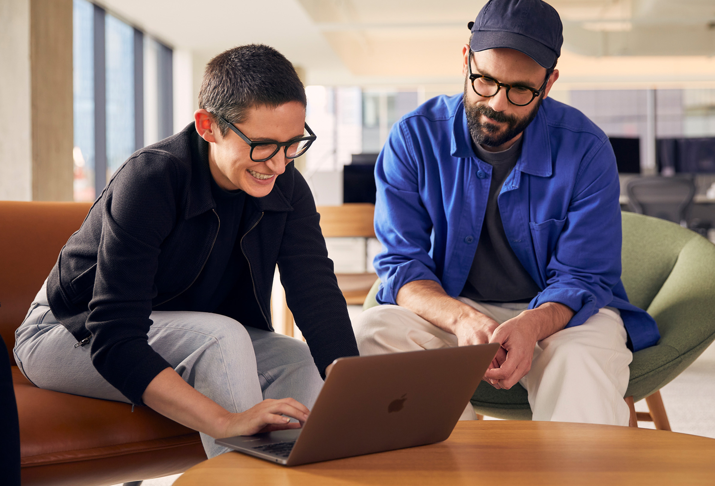 Zwei Apple Teammitglieder arbeiten an einem MacBook zusammen.