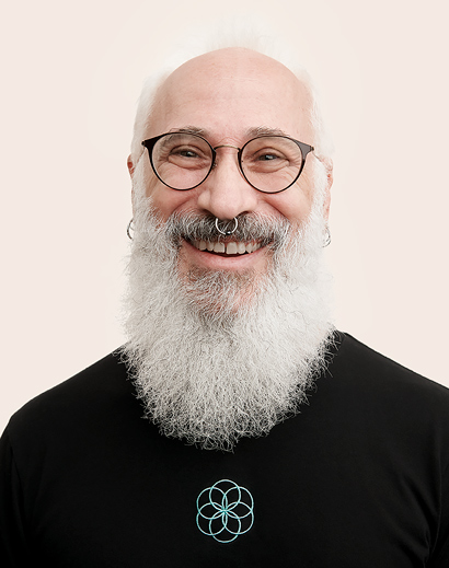 Membre de l’équipe Apple Retail avec une barbe blanche, qui sourit à l’objectif.
