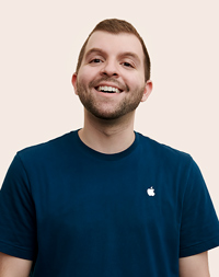 Un dipendente Apple Retail che sorride e tiene la testa leggermente inclinata verso l’alto.