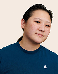 Una dipendente Apple Retail con i capelli lunghi che sorride guardando verso l’obiettivo.