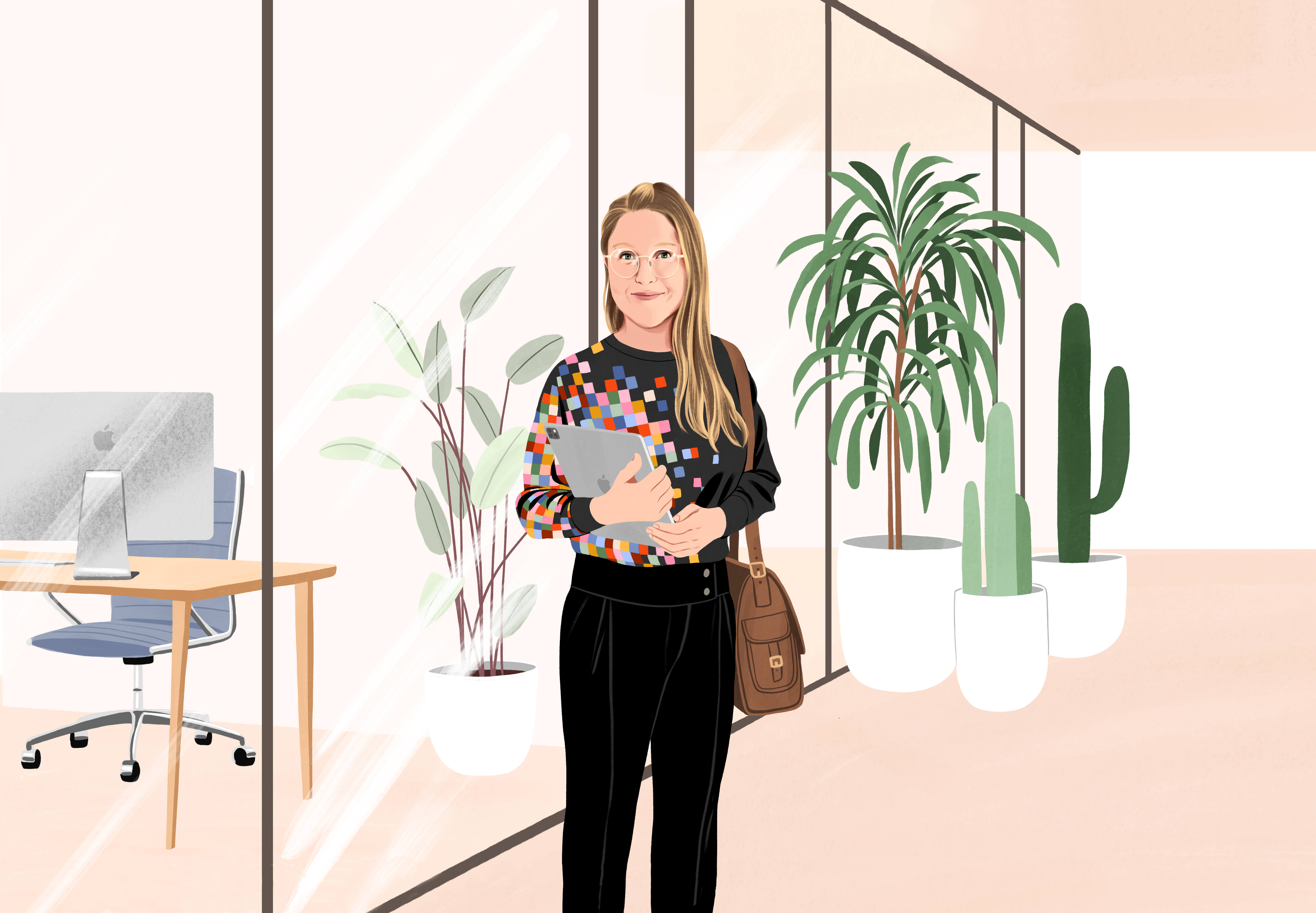Manuela in piedi sorridente in una sala dell’ufficio, con un iPad in mano e una borsa a spalla. Indossa pantaloni neri e una maglia nera con un motivo con pixel colorati.