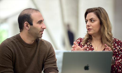 Desireh, sentada frente a una MacBook, habla con un compañero