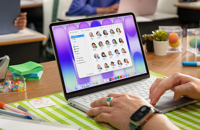 A teacher sits with an open Mac, and the Classroom app shows a full student list onscreen