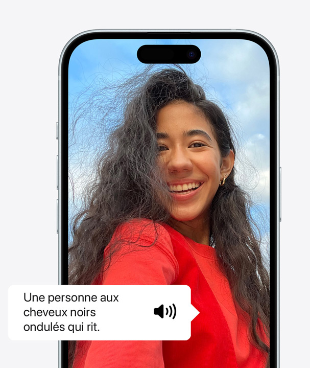 A picture of an iPhone using VoiceOver to describe the details of a person on screen laughing with wavy hair.